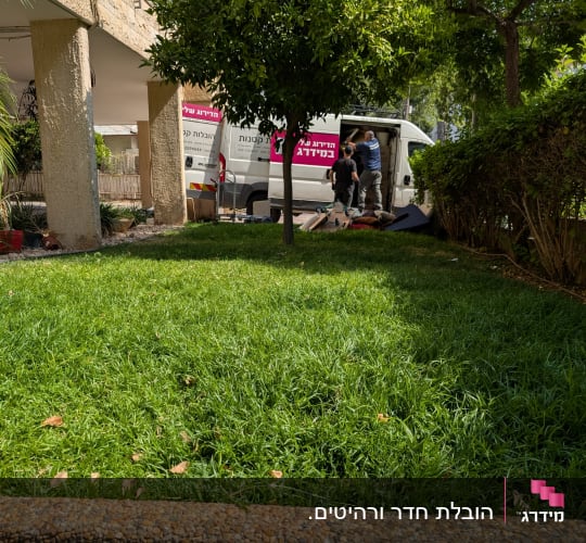 שני אנשים מעמיסים ציוד לרכב מסחרי לבן